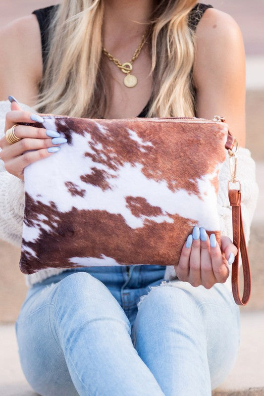 Faux Fur Cow Animal Print Clutch held by a woman, showcasing trendy ladies fashion in a stylish boutique setting.