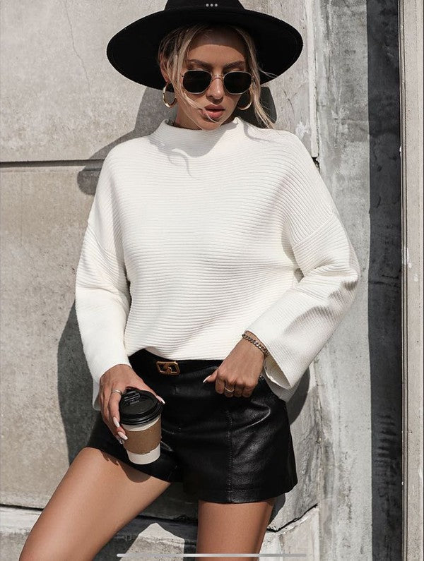 Knit ribbed sweater worn with a black leather skirt and hat, showcasing women’s fashion from a stylish women’s boutique.