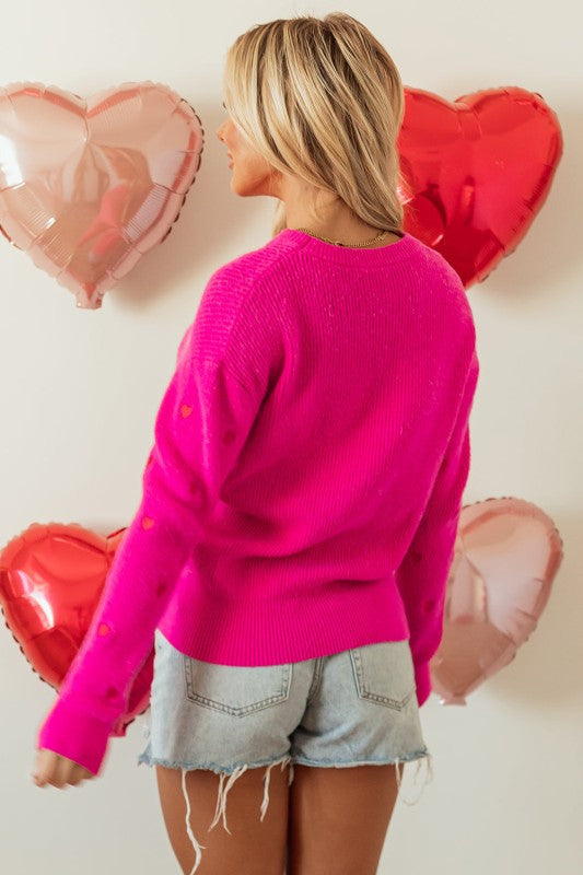 Gracie Heart Sweater in bright pink paired with shorts, perfect for women’s trendy tops at a women’s boutique.