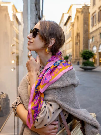 Stylish woman in sunglasses and colorful scarf showcasing trendy ladies fashion at a women's boutique.